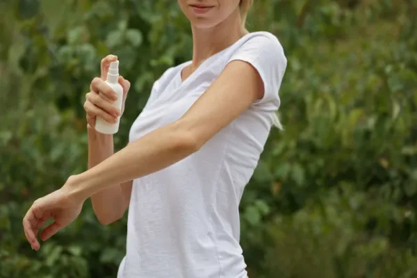Woman using insect repellent spray outdoors
