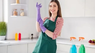 woman putting on rubber gloves to clean the kitchen.