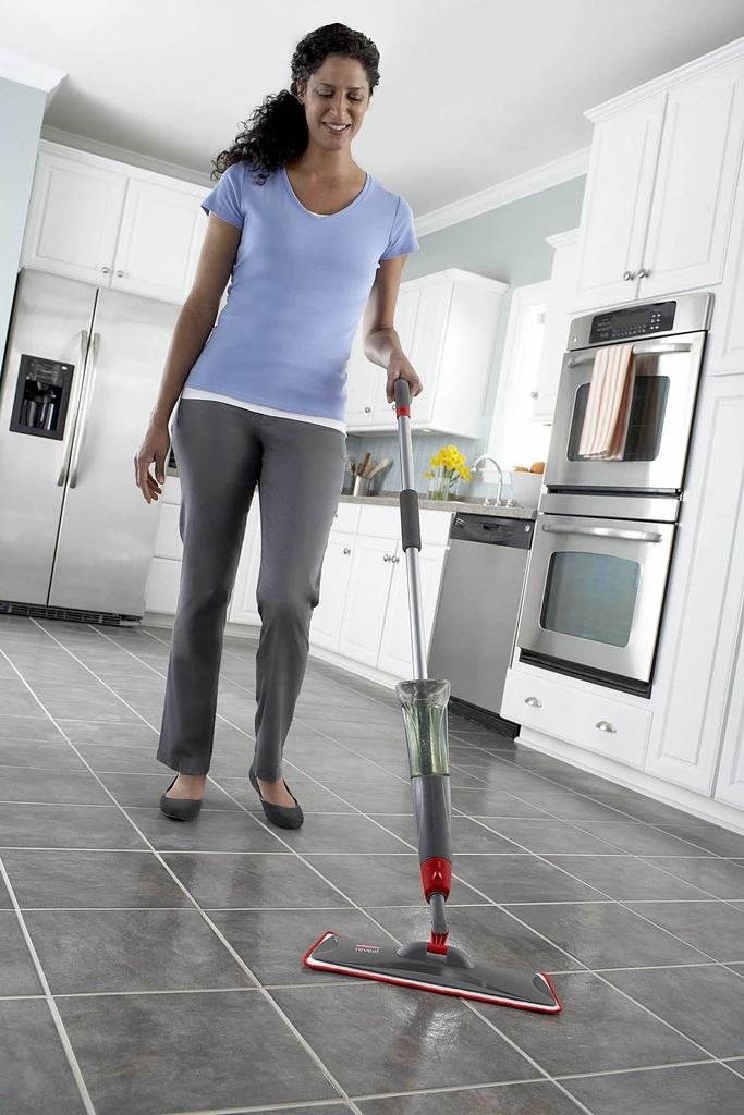 Woman cleaning a kitchen floor with a spray mop. Photo Cred: Rubbermaid Products on Flickr.