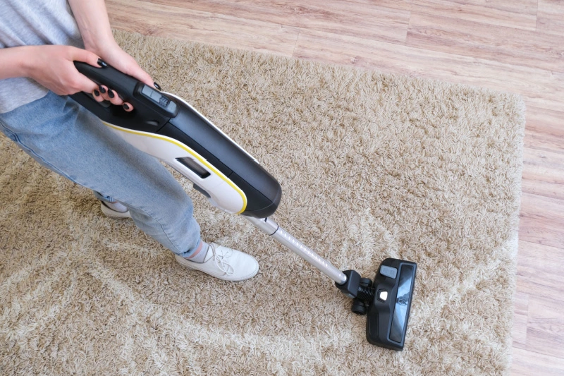 Person vacuuming carpet in living room.