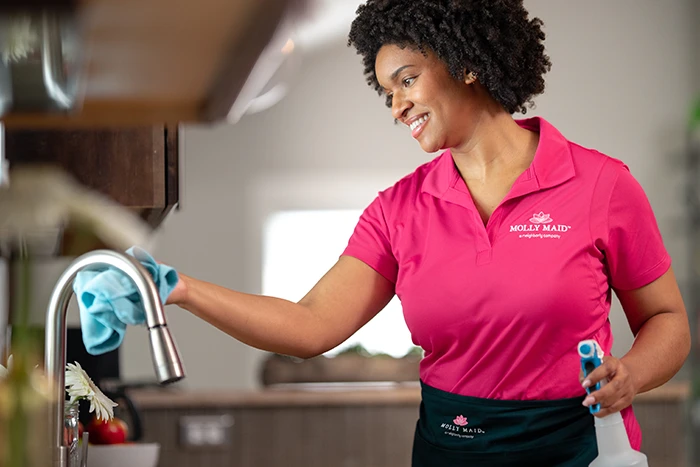 A Molly Maid professional wiping a sink during a short-term rental cleaning appointment.