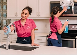 Two Molly Maids cleaning a kitchen together.