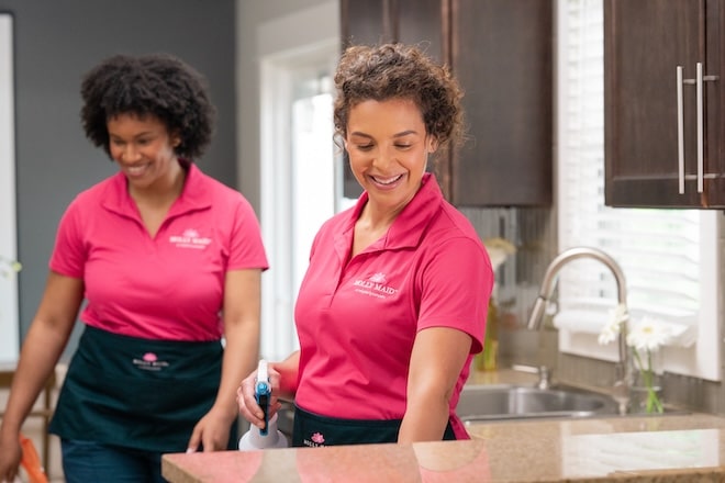 Two Molly Maid professionals cleaning a kitchen.