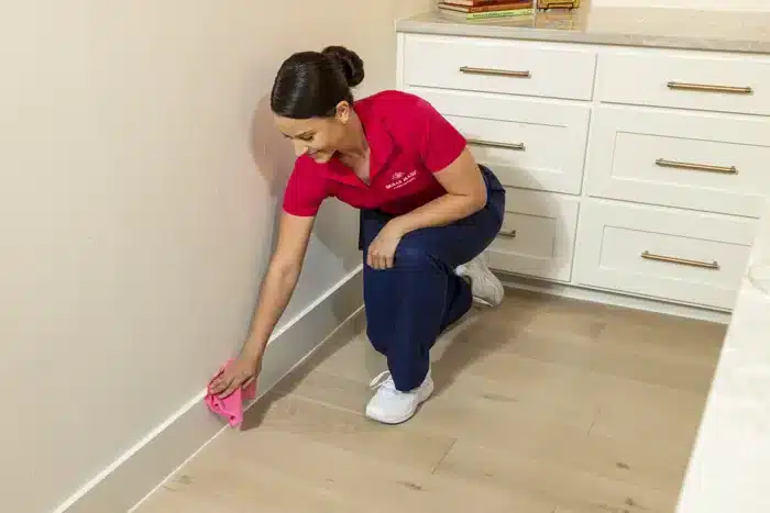 Molly Maid professional diligently cleaning an apartment baseboard.