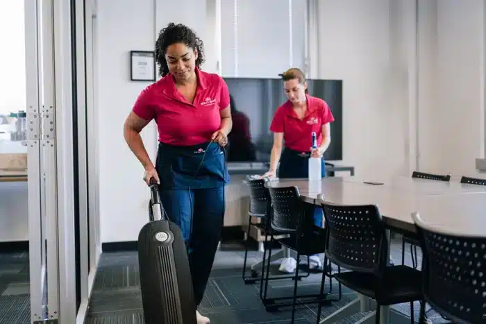 Molly Maid team cheerfully cleaning a conference room.