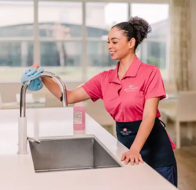 Molly Maid cleaning professional wiping a kitchen faucet