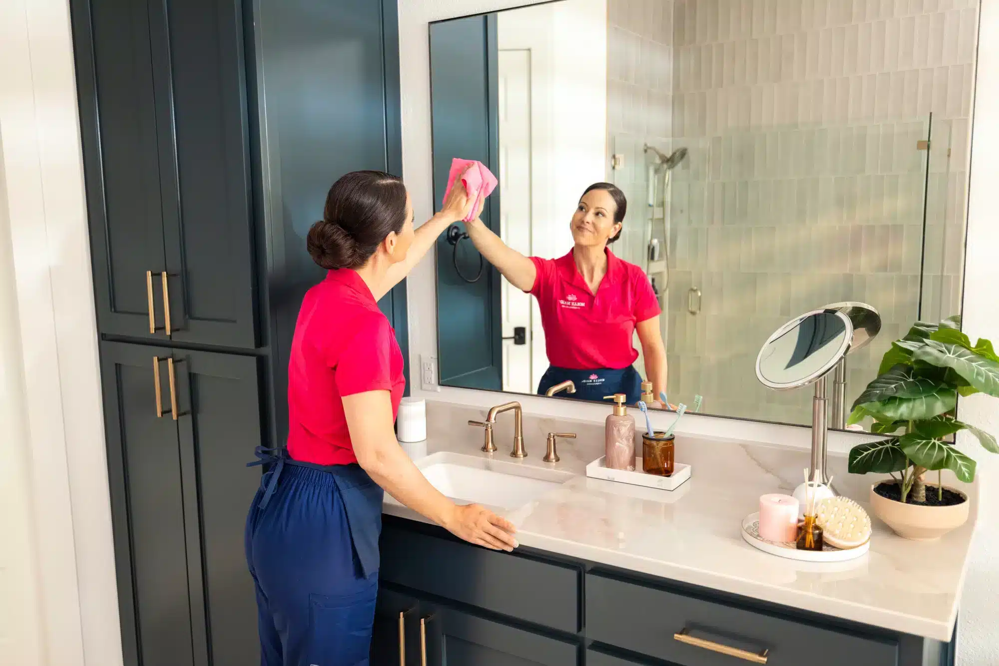 Molly Maid cleaning professional wiping a bathroom mirror