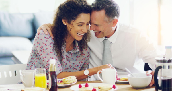 An affectionate couple enjoying New Year&rsquo;s breakfast in a clean kitchen.
