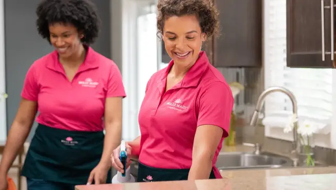 Two Molly Maid professionals cleaning a kitchen.