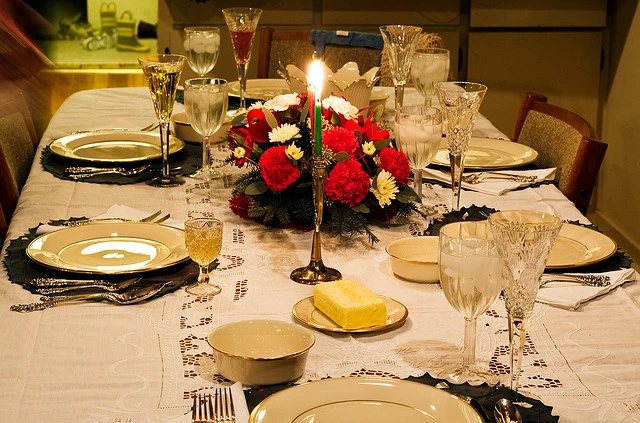 A table set with china, wine glasses, lit candles, and a floral centerpiece. Photo Cred: David Goehring on Flickr.