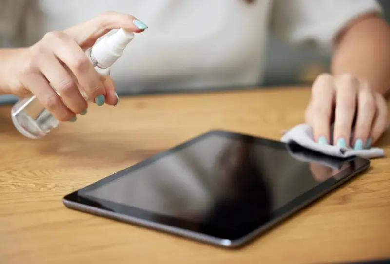 Person disinfecting touchscreen device.