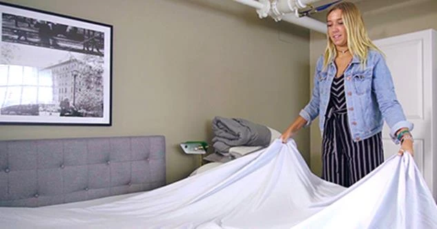 woman putting sheets on a bed
