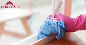 Person wearing a rubber glove dusting a window track