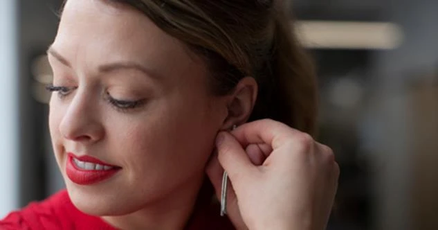 woman placing earring in her ear