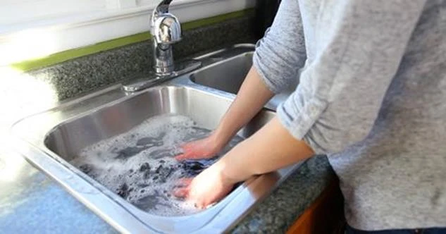 A person washing clothes in a sink