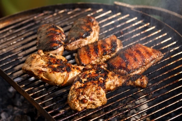 chicken being cooked on an outdoor charcoal grill