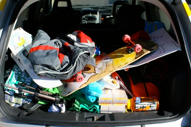 The trunk of a car crammed with a skateboard, outdoor gear, and other items. Photo Cred: Bugsy on Flickr.