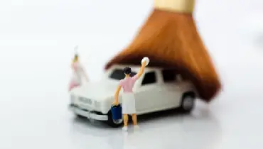 Miniature people around a small toy car