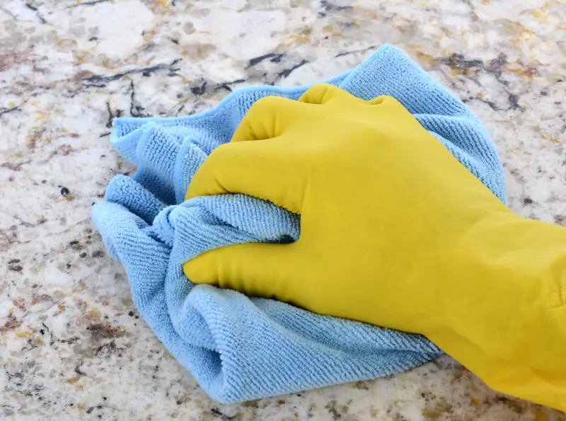 Person wiping granite counter top with microfiber cloth