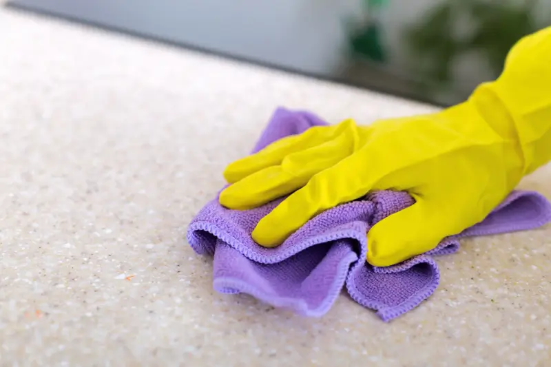 Person dusting granite counter top with microfiber cloth