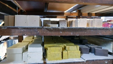 Freshly made natural soaps left to dry on wooden shelves, part of the natural soap making process.