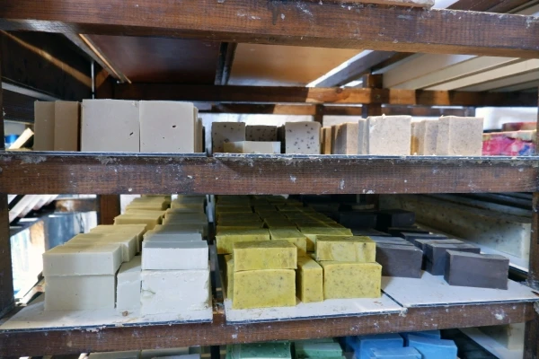 Freshly made natural soaps left to dry on wooden shelves, part of the natural soap making process.
