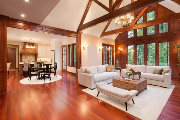 A grand living-dining area of a home with vaulted ceilings, wood beams, and rich hardwood floors throughout