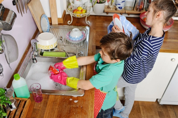 Two young children doing dishes in the kitchen