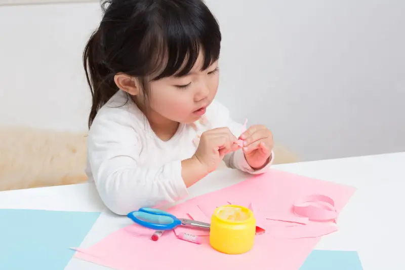 Young girl doing crafts with glue.