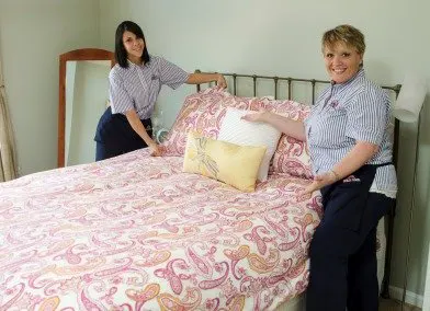 two molly maid employees making a bed 