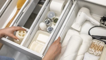 Top view of woman hands neatly organizing bathroom amenities and toiletries in bathroom drawer.