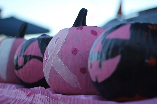Decorated pumpkins on a table, with one painted with the breast cancer awareness ribbon. Photo cred: North Charleston on Flickr.