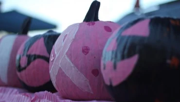 Decorated pumpkins on a table, with one painted with the breast cancer awareness ribbon. Photo cred: North Charleston on Flickr.