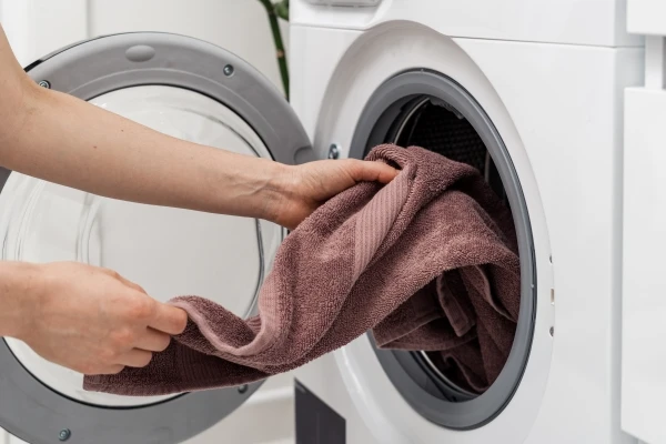 Person removing a brown colored towel from a washing machine