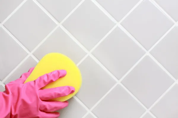 Hand in a glove cleaning the bathroom tiles