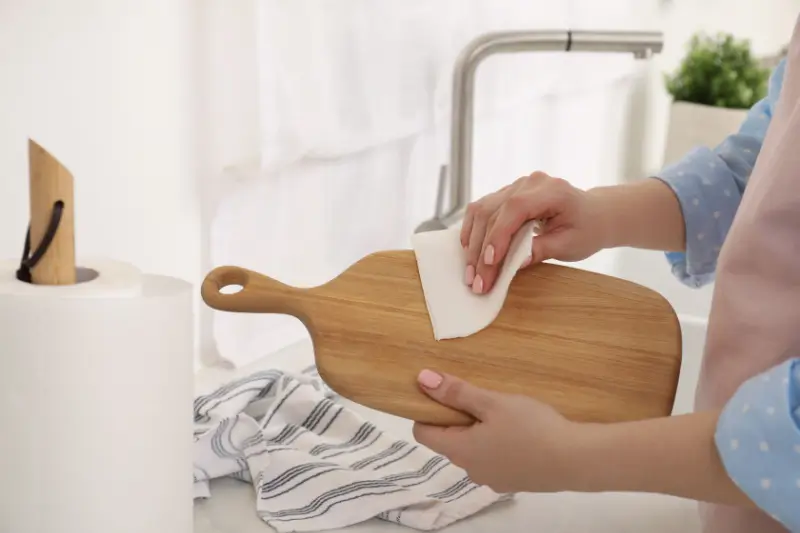 Person cleaning wood cutting board