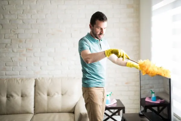 Man dusting his living room furniture