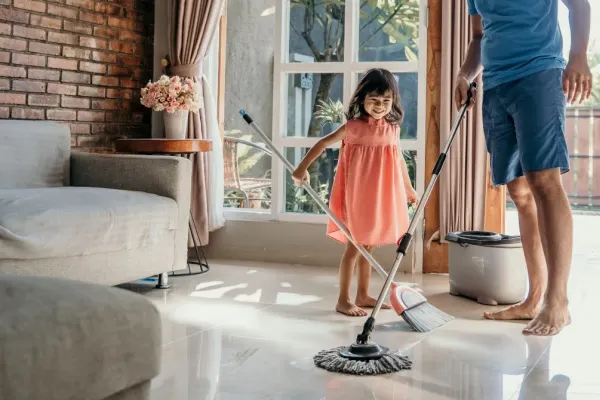Father and daughter cleaning living room floor together