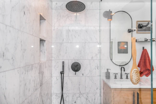 A bright, clean, modern shower with marble tile and glass door. Photo by Zac Gudakov on Unsplash.