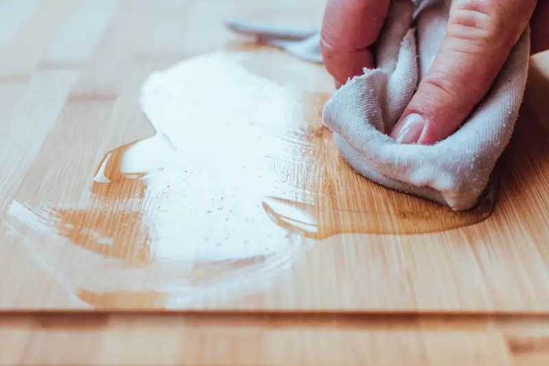 Person applying mineral oil to wooden cutting board