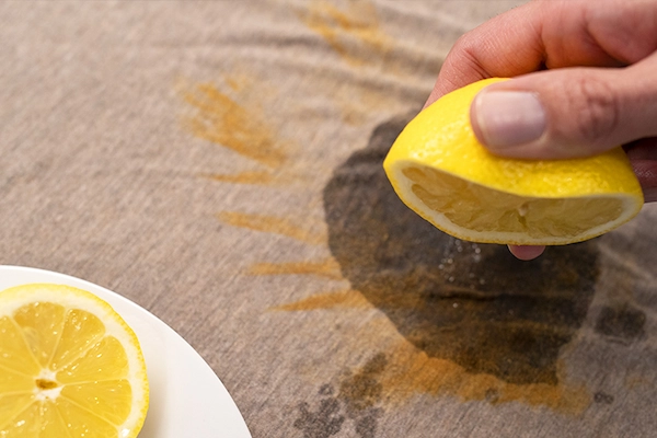 Person squeezing lemon juice onto fabric with rust stain.