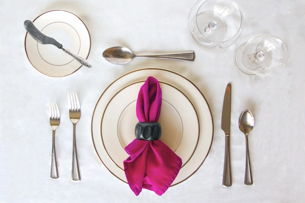 Overhead view of simple, elegant table setting with magenta cloth napkin.