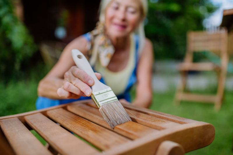 Woman staining wood patio furniture