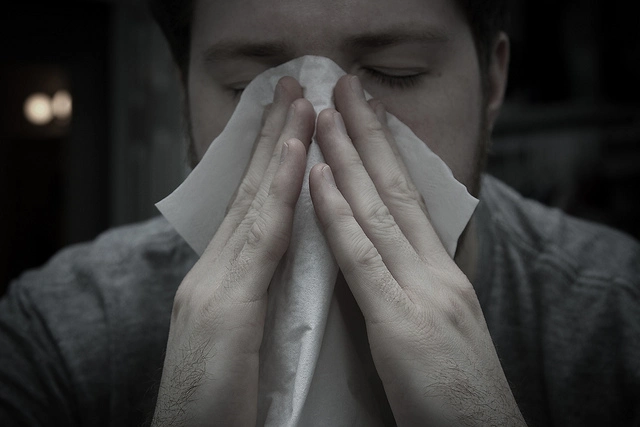 Man blowing his nose into a tissue. Photo Cred: William Brawley on Flickr.
