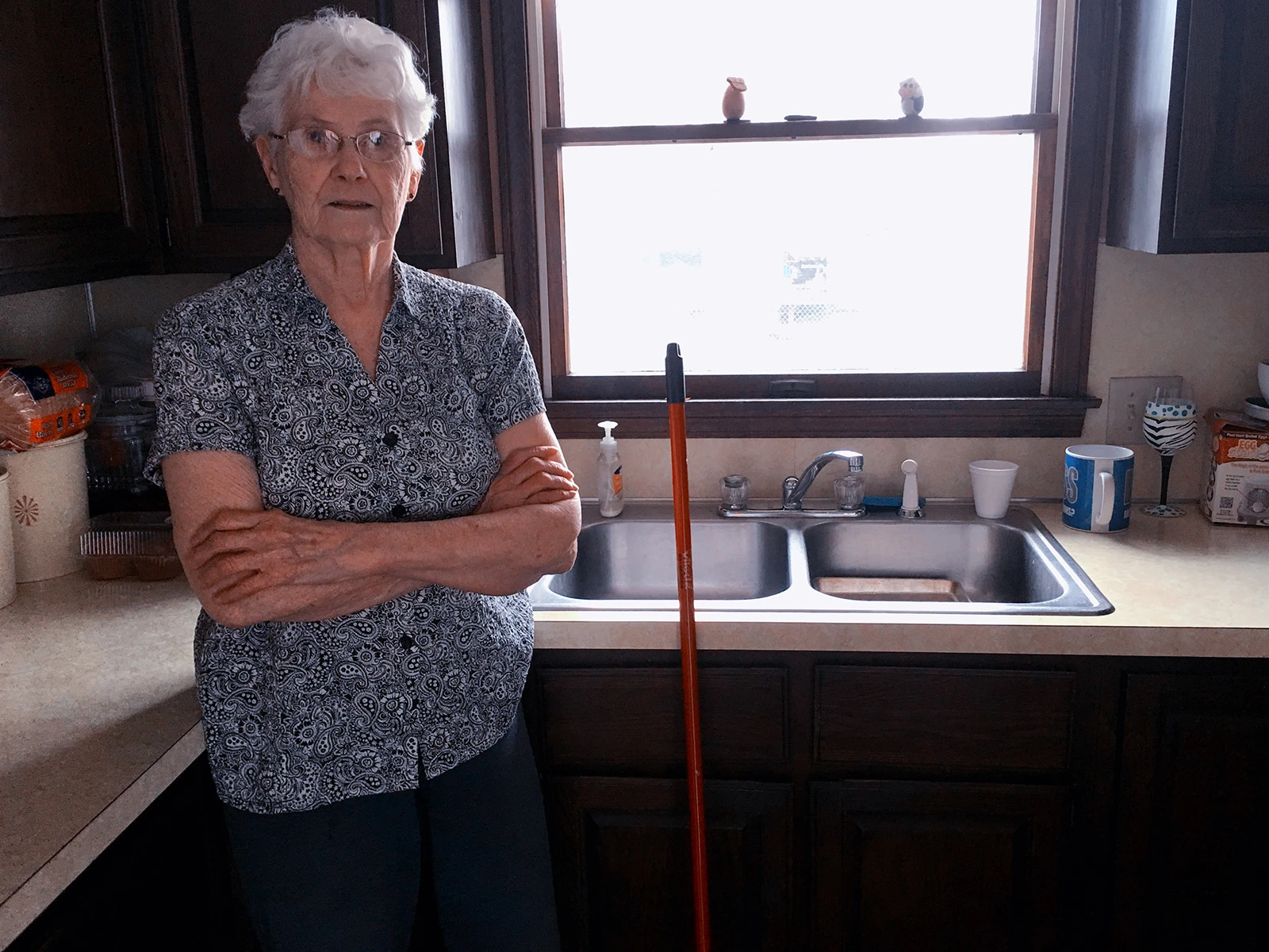 Grandmotherly figure standing in the kitchen with arms crossed