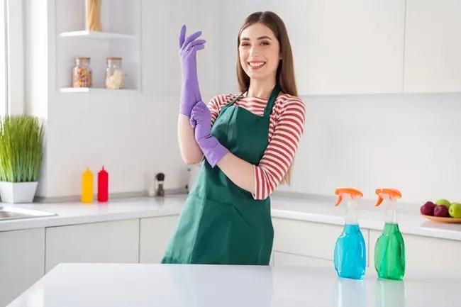woman putting on rubber gloves to clean the kitchen.