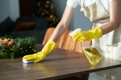 Woman cleaning a table decorated for Christmas.