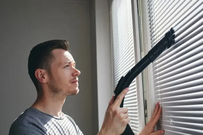 Man cleaning dust off blinds