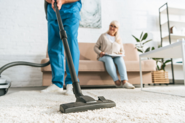 Man vacuuming living room for his elderly mother