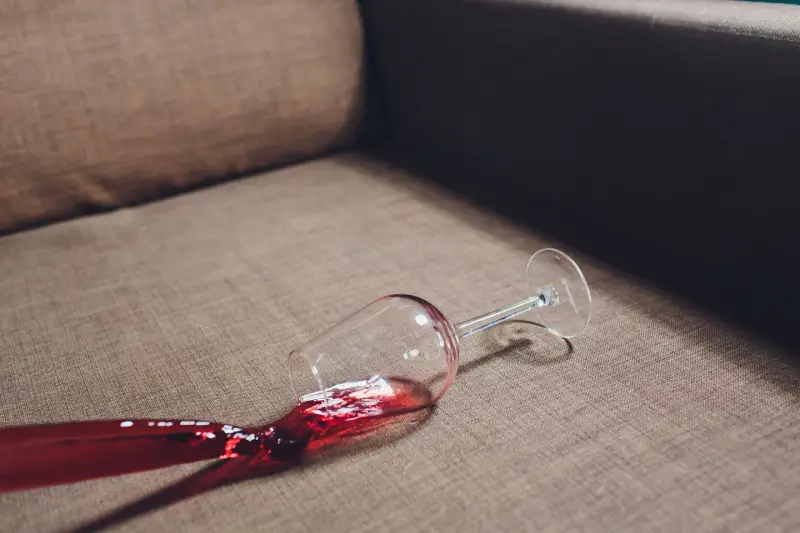 Wine glass spilling on couch